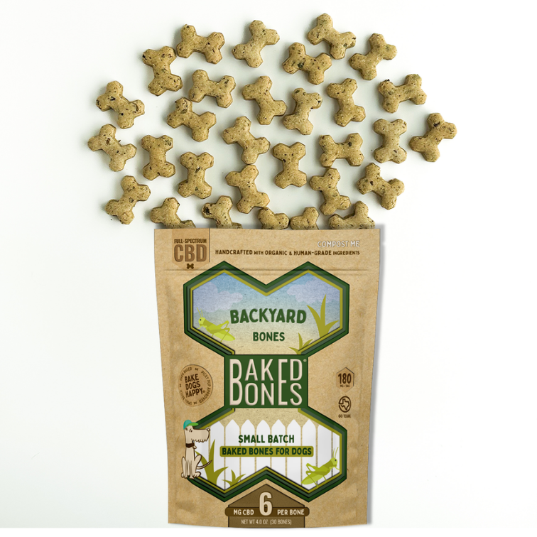 Light brown baked dog bones with flecks of dark green spilling out of a Kraft BakedBones bag with a green bone and “BACKYARD BONES” on the front